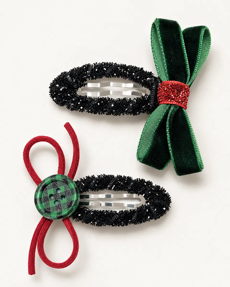The Christmas bow clips on a white background: black tinsel with a green velvet bow, and black tinsel with a red cord bow and a check button