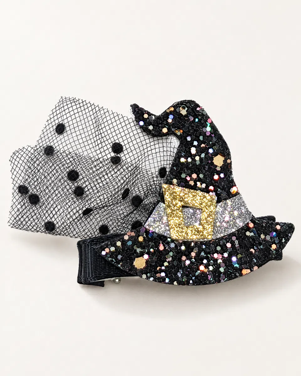 The mini witch hat clip on a white background: a flat witch hat in black glitter and sequins, with a silver band, a gold buckle and black polka-dot tulle